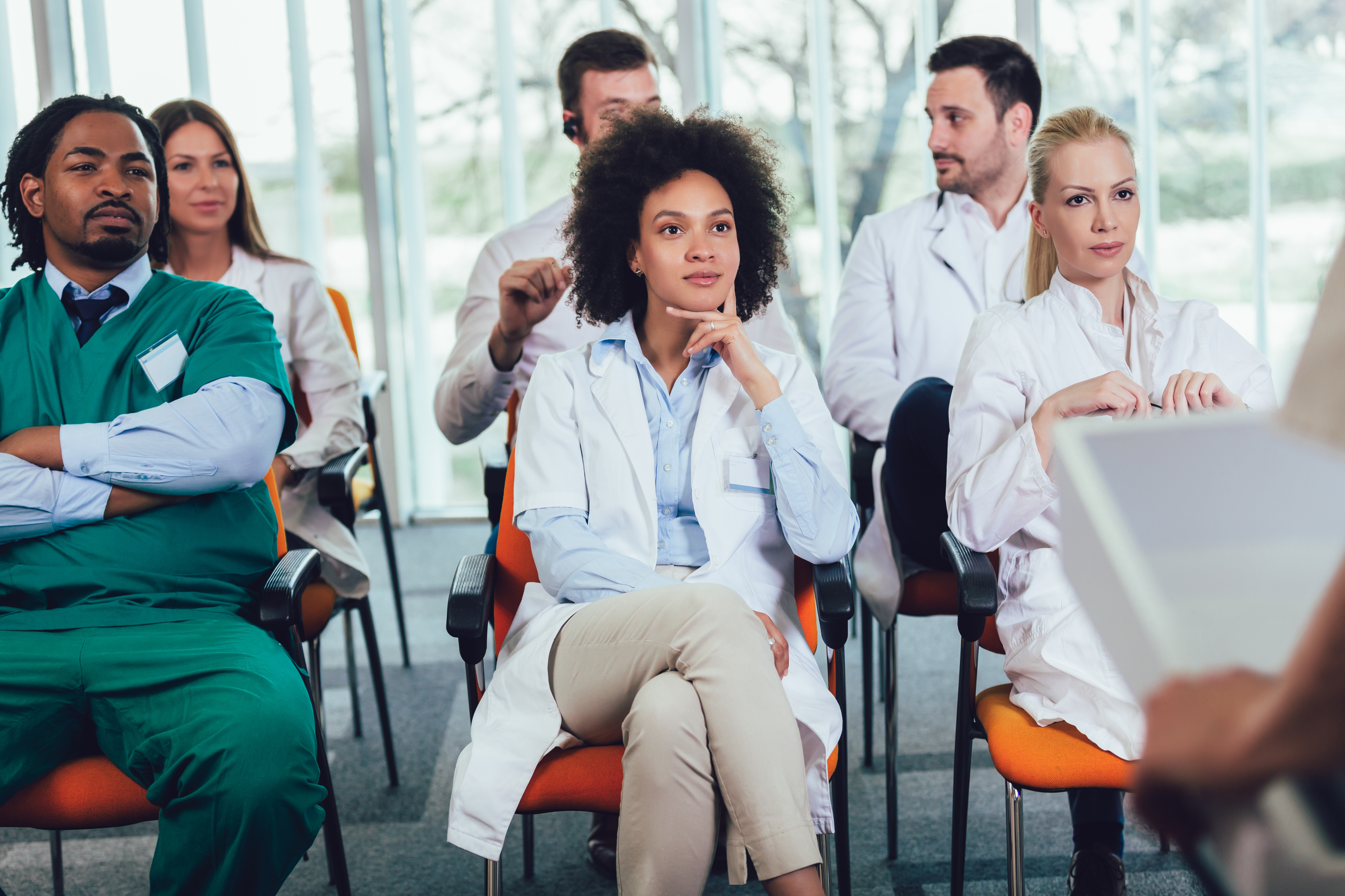 Medical students in white coats and scrubs attending a lecture